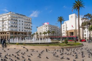 Mohammed V Square in Casablanca with fountains, palm trees, Art Deco buildings, and city traffic