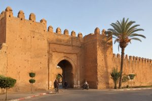 Historic gate and ochre ramparts of Taroudant with local residents entering the medina