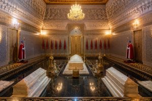 Interior of the Mausoleum of Mohammed V in Rabat, Morocco, featuring marble royal tombs, intricate zellige mosaics, carved cedar wood, ornate chandeliers, and traditional Moroccan architecture