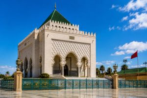 Mausoleum of Mohammed V in Rabat, Morocco, featuring its white marble architecture, green tiled roof, ornate arches, and ceremonial royal setting beside Hassan Tower