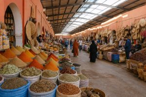 Colorful spice stalls and shoppers inside Souk El Had market in Agadir